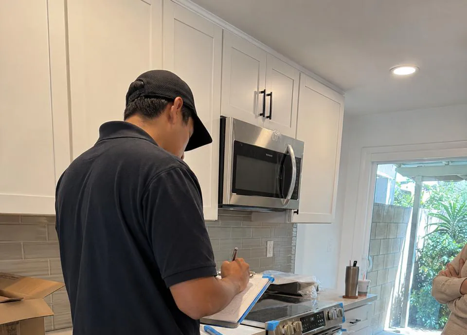 Appliance repair technician servicing a built-in refrigerator in a Brea, California hillside kitchen