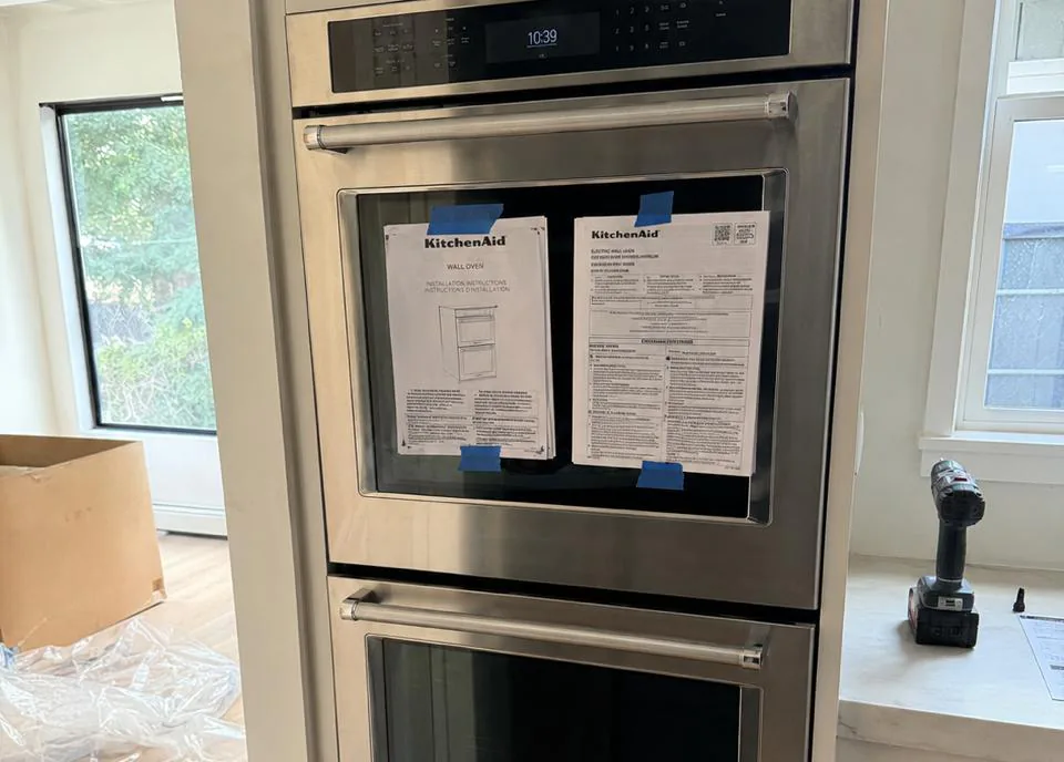 Appliance repair technician servicing a refrigerator in an Encinitas, California coastal home